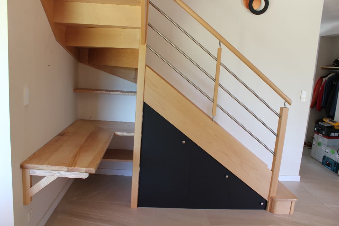 Agencement sous escalier. Bureau, étagères et placard.