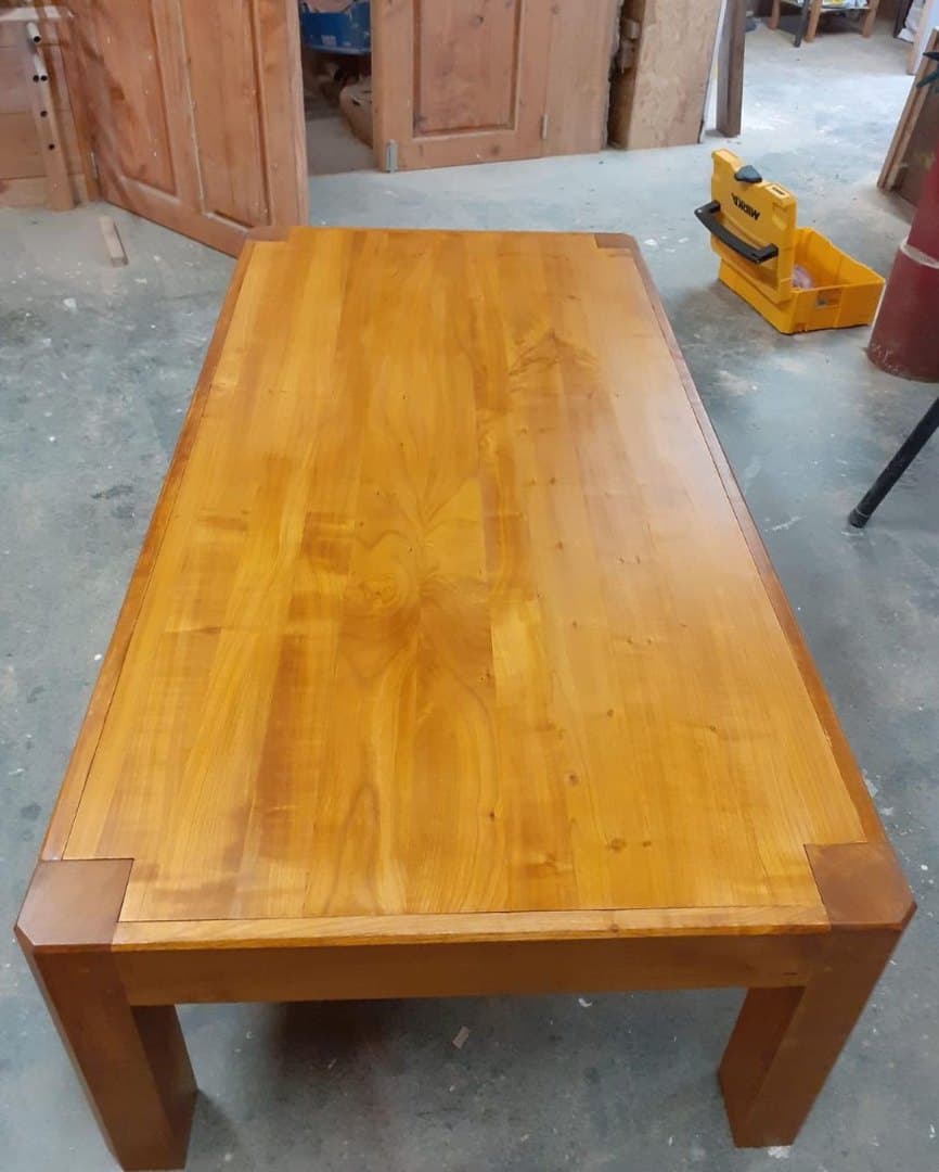 Table basse en merisier. Une teinte à l'eau est appliquée en dessous du vernis. Dans un style contemporain, le plateau est encastré dans le piétement.